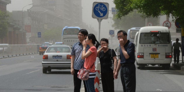 People try to protect themselves against air pollution and dust along a street in Beijing on May 19, 2013. China will more than double the number of cities covered by air quality monitoring, as part of efforts to tackle heavy smog that has sparked huge public anger. Swathes of acrid haze have repeatedly shrouded large parts of the country in recent months, provoking outrage among Internet users and unusual outspoken calls for action, in the state-run media. AFP PHOTO / Mark RALSTON (Photo credit should read MARK RALSTON/AFP/Getty Images)