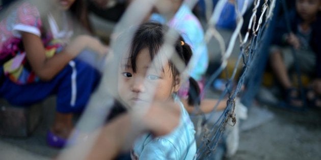 TACLOBAN, PHILIPPINES - NOVEMBER 14: Children shletering in a school building with their families sit on the stairs in typhoon-ravaged Tacloban city on November 14, 2013 in Philippines. Haiyan, possibly the most powerful typhoon on record, killed thousands of people upon hitting the Philippines and hundred of thousands flee and houses are blown to pieces. The death toll is feared to rise as the worst-hit areas slowly become accessible. (Photo by Onur Coban/Anadolu Agency/Getty Images)