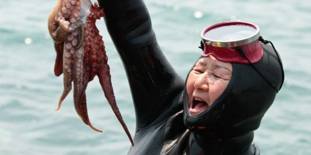 A jubilant Haenyeo (Jeju diving woman) proudly raises her catch at the 5th annual Haenyeo Diving Festival on Jeju Island, South Korea