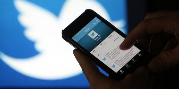 A user scrolls through a Twitter feed on the screen of an Apple Inc. iPhone 5 smartphone in this arranged photograph taken in London, U.K., on Friday, Oct. 4, 2013. Twitter Inc.'s initial public offering documents suggested a valuation of $12.8 billion for the microblogging service, underscoring the seven-year rise of a still unprofitable company that has helped revolutionize how people share information. Photographer: Chris Ratcliffe/Bloomberg via Getty Images