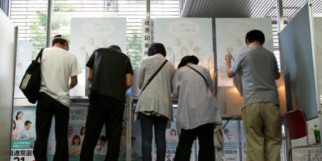 Voters fill out their ballots for the Japanese parliament's upper house election at a polling station in Tokyo, Japan, on Sunday, July 21, 2013. Japanese voters are set to hand Prime Minister Shinzo Abe control of both houses of Parliament, giving him a mandate to extend his overhaul of the world's third-biggest economy. Photographer: Kiyoshi Ota/Bloomberg via Getty Images