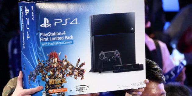 The first customer to purchase the PlayStation 4 (PS4) video game console, left, holds up the box as Hiroshi Kawano, president of Sony Computer Entertainment Japan Asia, looks on at the launch of the PS4 console at the Sony showroom in Tokyo, Japan, on Saturday, Feb. 22, 2014. Sony Corp., its credit rating cut to junk by Moody's Investors Service as Japan's biggest television maker struggles to capture consumer demand for smartphones and tablet computers, released the PS4 console in Japan today. Photographer: Tomohiro Ohsumi/Bloomberg via Getty Images