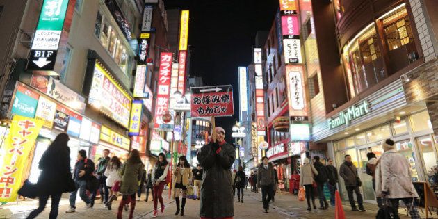 An employee holds a sign for a 'okonomiyaki' restaurant at night in the Shibuya district of Tokyo, Japan, on Sunday, Feb. 16, 2014. Japans economy grew at a pace slower than any economist surveyed by Bloomberg News forecast in the fourth quarter, underscoring risks to the recovery as a sales-tax increase looms in April. Photographer: Yuriko Nakao/Bloomberg via Getty Images