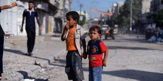 Two Palestinian boys hold hands as they look at the bombed out remains of a mosque that was targeted by Israeli air strikes at the Nuseirat refugee camp in the Central Gaza Strip early on August 10, 2014. Palestinian negotiators have warned they will leave Cairo on August 10 if their Israeli counterparts do not show up for truce talks, after Israel pummelled Gaza with fresh air strikes that killed at least 10 Palestinians. AFP PHOTO/ROBERTO SCHMIDT (Photo credit should read ROBERTO SCHMIDT/AFP/Getty Images)