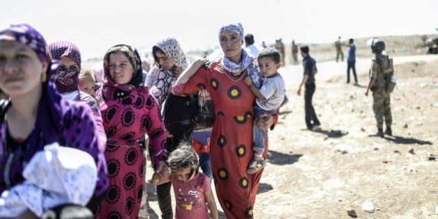 Syrian Kurd families carry their belongings after they crossed the border between Syria and Turkey near the southeastern town of Suruc in Sanliurfa province, on September 20, 2014. Several thousand Syrian Kurds began crossing into Turkey on September 19 fleeing Islamic State fighters who advanced into their villages, prompting warnings of massacres from Kurdish leaders. Turkey on September 19 reopened its border with Syria to Kurds fleeing Islamic State (IS) militants, saying a 'worst-case scenario' could drive as many as 100,000 more refugees into the country. AFP PHOTO/BULENT KILIC (Photo credit should read BULENT KILIC/AFP/Getty Images)