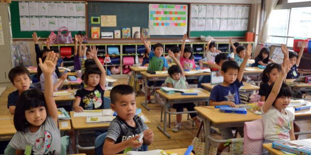 THIS IMAGE IS PART OF A PHOTO PACKAGE ON CHILDREN GOING TO SCHOOL AROUND THE WORLDSix-year-old Japanese elemetary student Seishi Nishida (2nd row R blue shirt) raises his hand along with classmates at school in Tokyo on June 11, 2013. AFP PHOTO / Yoshikazu TSUNO (Photo credit should read YOSHIKAZU TSUNO/AFP/Getty Images)