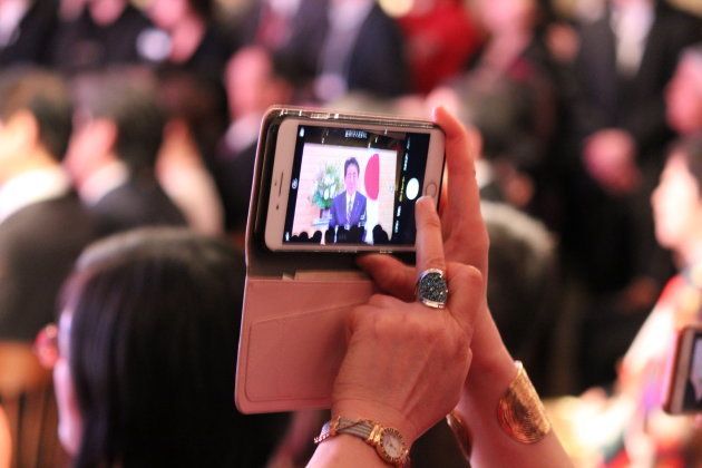 安倍総理のビデオメッセージにカメラを向ける参加者