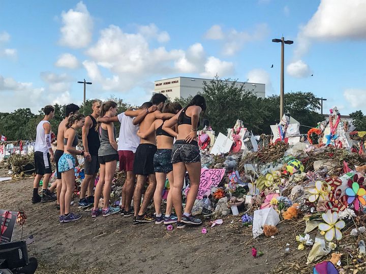 Students from Marjory Stoneman Douglas High School's cross country team stop by the makeshift memorials in front of the school on March 28, 2018.
