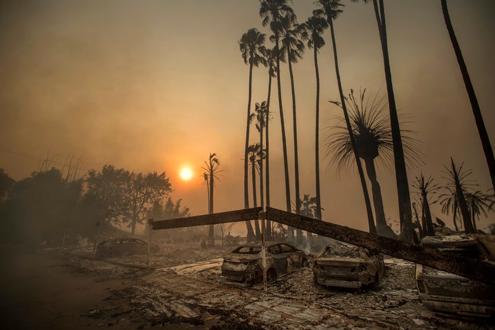 In this Dec. 5, 2017 file photo, smoke rises behind a destroyed apartment complex as a the Thomas wildfire burns in Ventura,