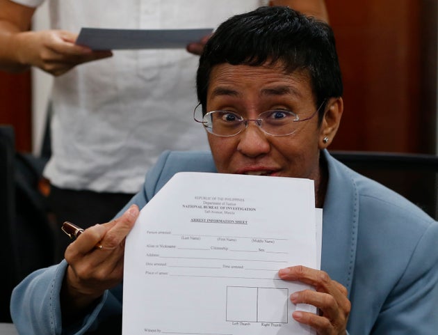 Maria Ressa shows an arrest form after being arrested by National Bureau of Investigation agents in a...