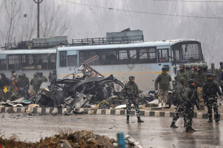 Security forces near the damaged vehicles at Lethpora on the Jammu-Srinagar highway, on February 14, 2019 in Srinagar.