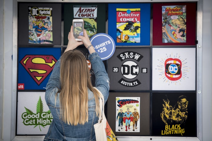 An attendee takes a photograph of DC comic book-themed shirts for sale at the South By Southwest conference in Austin, Texas, in March 2018.