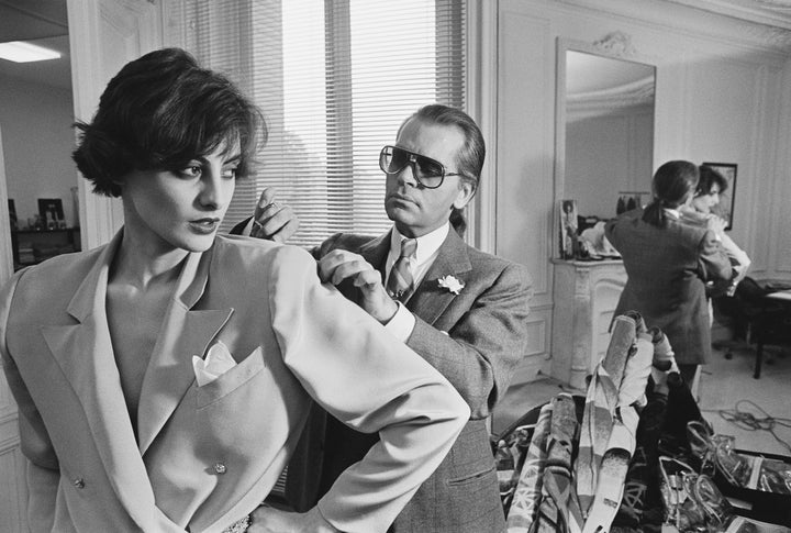 Karl Lagerfeld fits one of his designs on top model Ines de la Fressange at Chloe's Paris studio in 1983. 