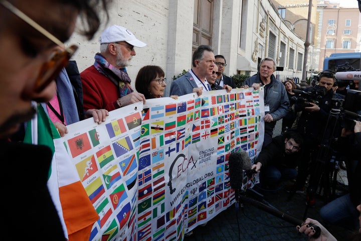 Sex abuse survivors and members of the ECA (Ending Clergy Abuse) hold their organization banner as they talk to journalists,