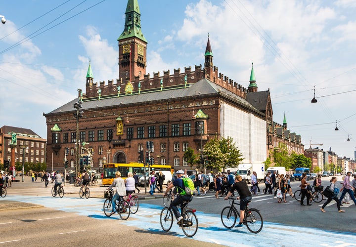 Cyclists cross the street on a dedicated bike line in front of the city hall in Copenhagen, Denmark.