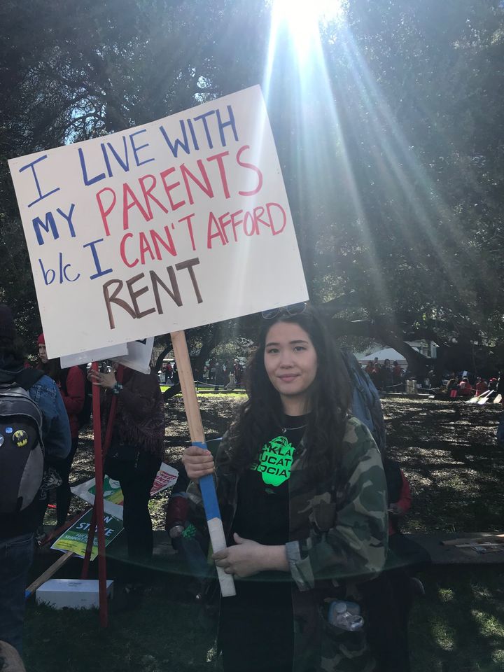 Laura Jetter, a sixth- to eighth-grade teacher at La Escuelita, holds a sign at the rally: &ldquo;I live with my parents beca