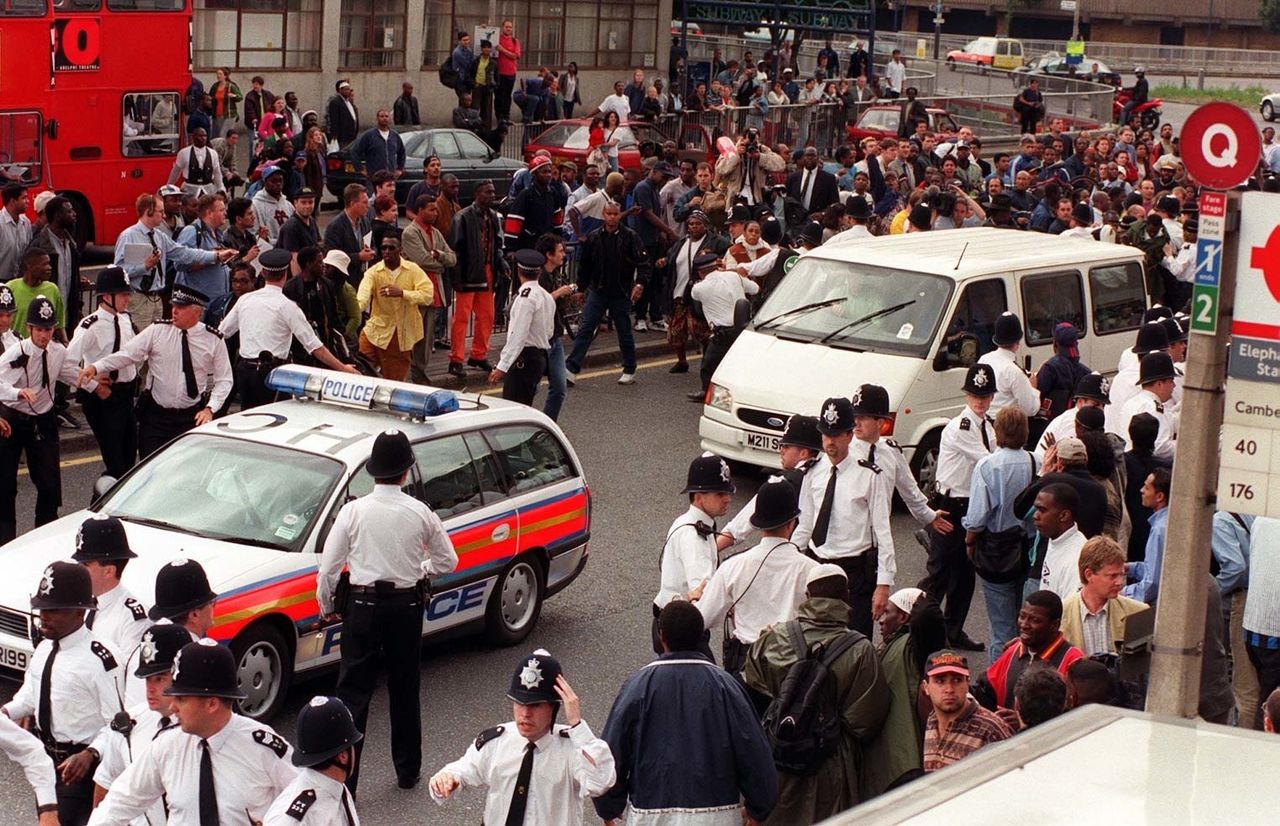 A police car leads a van transporting the five murder suspects away from the crowds of angry demonstrators after the two days of questioning in the Stephen Lawrence Murder Inquiry came to an end