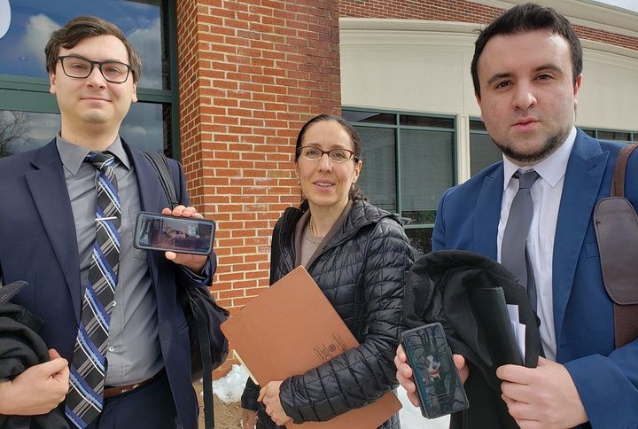 Rubin flanked by her two animal law clinic students earlier this month at the courthouse in Hartford, where they advocated for an abused dog in a legal case. Jesse Mangiardi, left, shows a cell phone picture of his two dogs, Thor and Luna, while Shaun Moloney, right, holds up a cell phone photo of his border collie, Jessica. 
