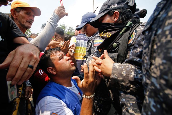 A supporter of Venezuela's opposition leader Juan Guaidó demonstrates in front of members of Venezuela's Bolivarian National Police, who are guarding the Francisco de Paula Santander International Bridge.