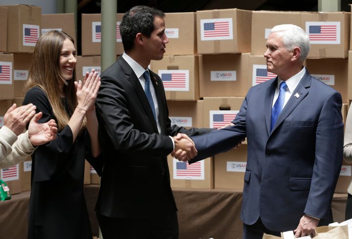 Venezuela's self-proclaimed interim president Juan Guaidó shakes hands with U.S. Vice President Mike Pence in a room filled with humanitarian aid destined for Venezuela.
