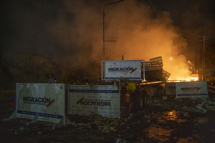 A truck previously loaded with humanitarian aid is in flames behind immigration barricades scattered across the Francisco De Paula Santander International Bridge.