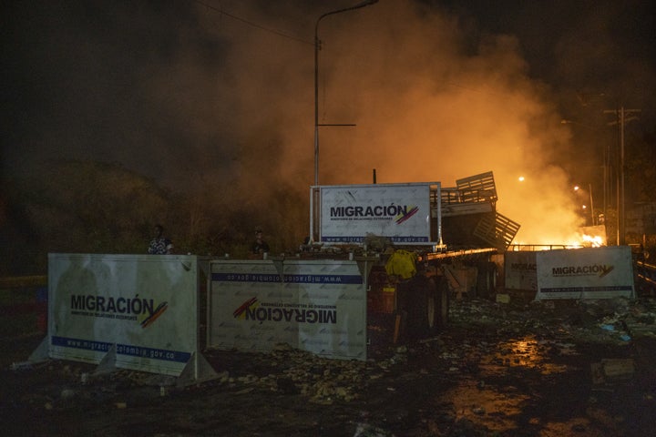 A truck previously loaded with humanitarian aid is in flames behind immigration barricades scattered across the Francisco De