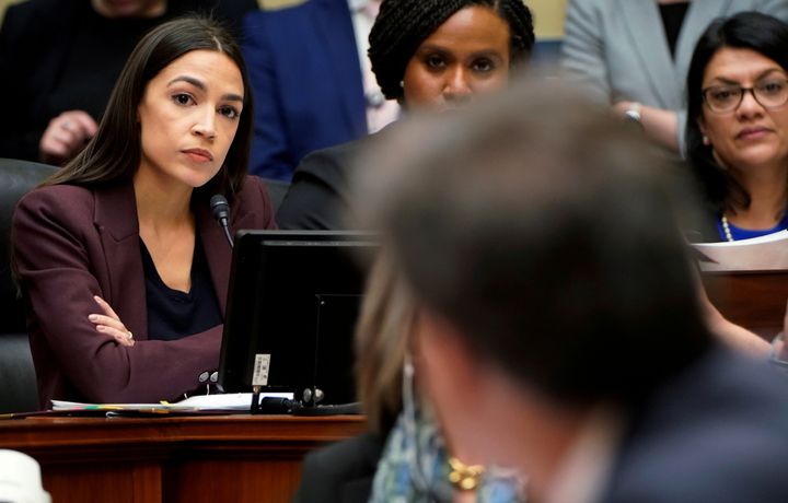 Rep. Alexandria Ocasio-Cortez (D-N.Y.), left, listens to former Trump personal attorney Michael Cohen answer one of her questions at a House Committee on Oversight and Reform hearing on Wednesday.