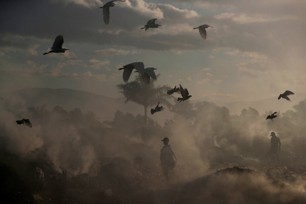 Locals walk among burning rubbish piles at the main garbage dump near Cite Soleil neighborhood in Port-au-Prince, Haiti, on Feb. 21, 2019. Credit: Ivan Alvarado / Reuters