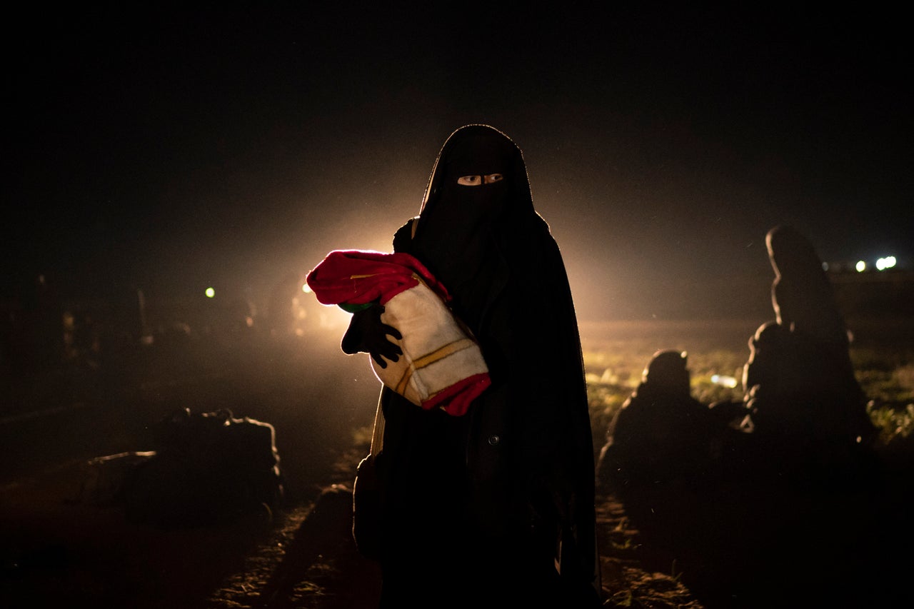 A woman who was evacuated out of the last territory held by Islamic State militants holds her baby after being screened by U.S.-backed Syrian Democratic Forces in the desert outside Baghouz, Syria, on Feb. 25, 2019.