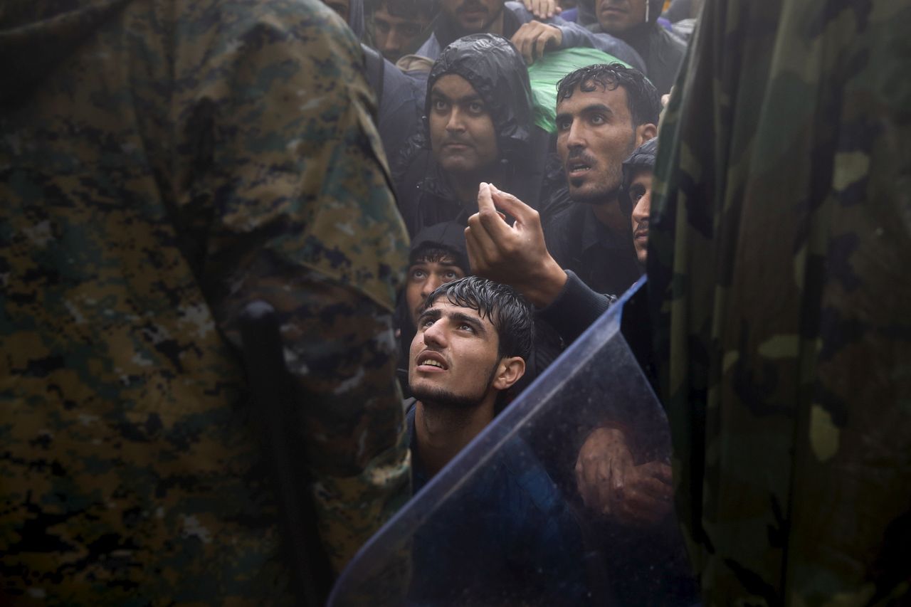 Πρόσφυγες και μετανάστες εκλιπαρούν αστυνομικούς να τους επιτρέψουν να περάσουν τα σύνορα από την Ελλάδα στη Βόρεια Μακεδονία. 10 Σεπτεμβρίου 2015. Το Reuters και η ομάδα του Γιάννη Μπεχράκη μοιράζονται το Βραβείο Πούλιτζερ με τους New York Times για τις φωτογραφίες της προσφυγικής κρίσης στην Ευρώπη.