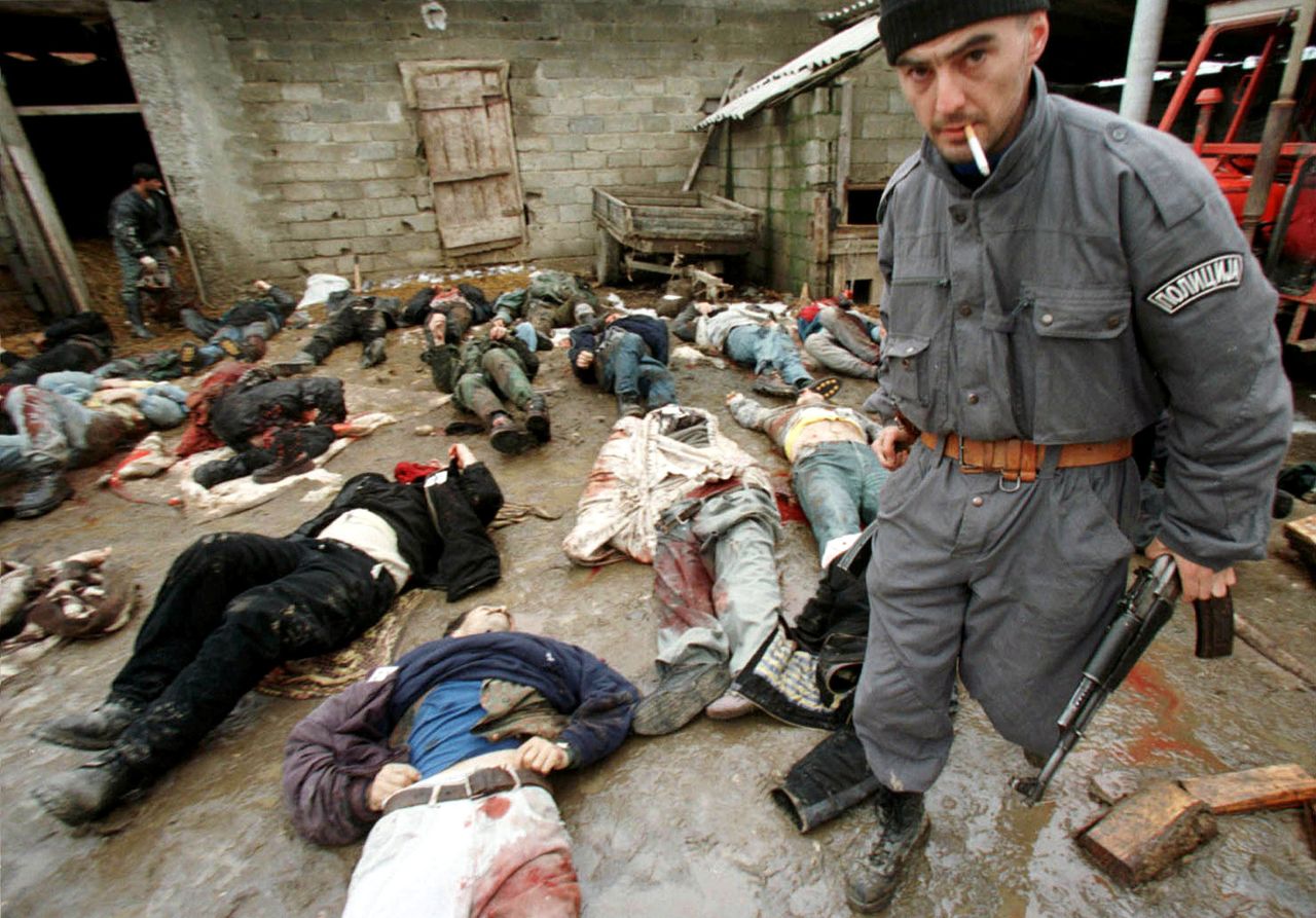 Σέρβος παίρνει το όπλο νεκρού Κοσοβάρου αντάρτη, ένα AK-47 και κοιτάζει στον φακό του Γιάννη Μπεχράκη. 29 Ιανουαρίου 1999, 65 χλμ δυτικά της Πρίστινα. Η σκηνή εφιαλτική. 