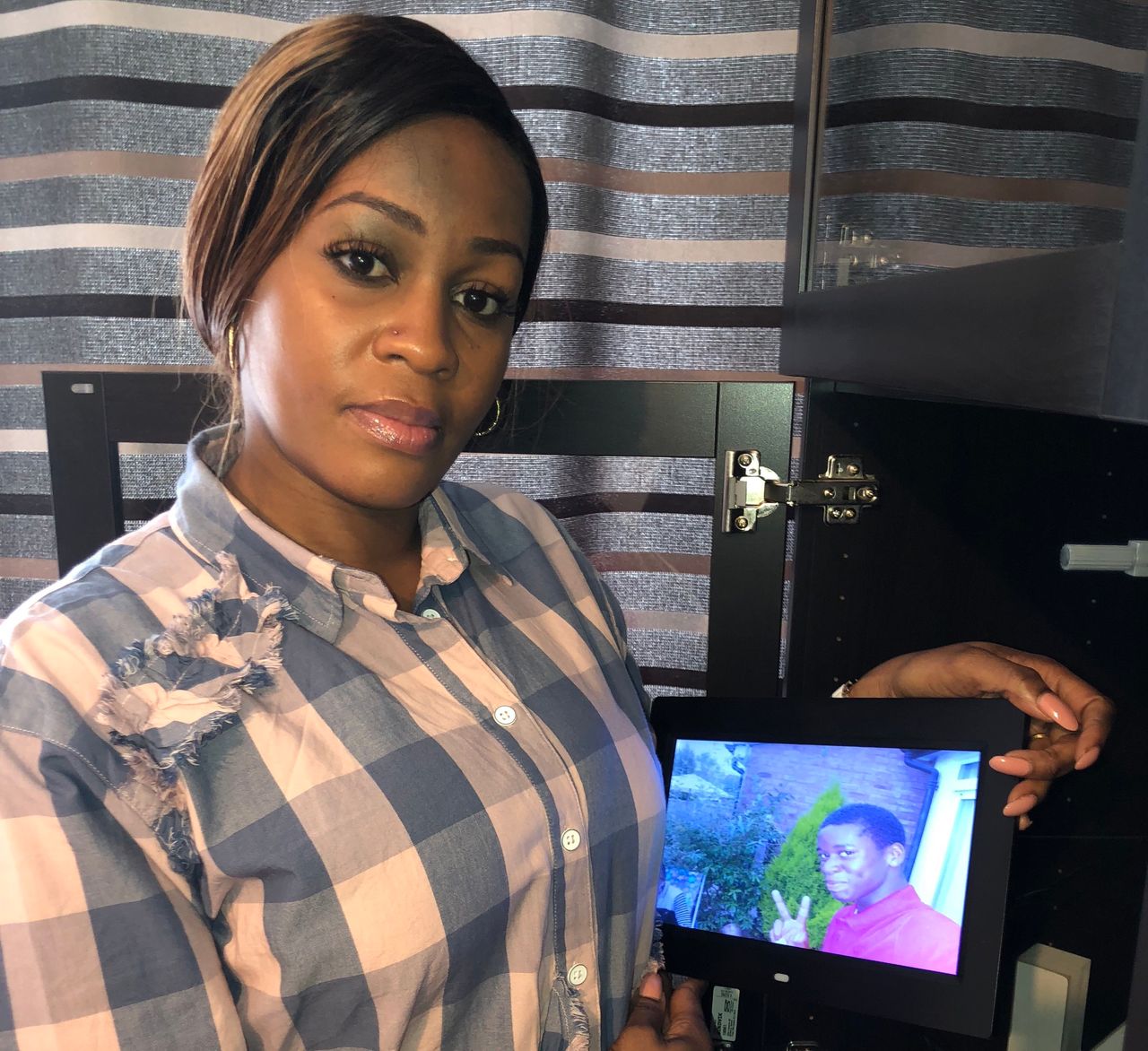 Peguy Kato holding a photograph of her son Champion, who was stabbed to death in 2013.