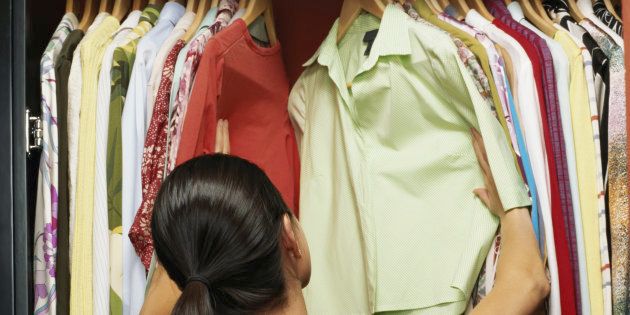 Young woman choosing clothes from wardrobe, rear view