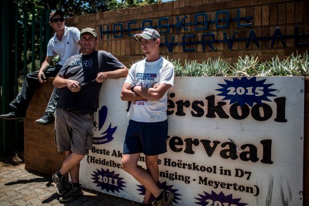 Pupils' parents and other members of the surrounding community stand behind a police line, in support of a protest against admission and language policies, outside the Horskool Overvaal school on January 19, 2018 in Vereeniging, South Africa. / AFP PHOTO / GULSHAN KHAN (Photo credit should read GULSHAN KHAN/AFP/Getty Images)