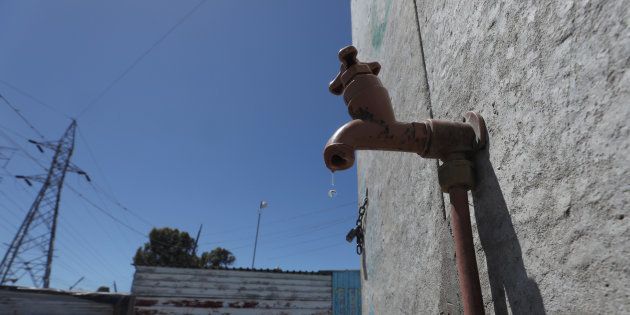 Residents walk past a leaking communal tap in Khayelitsha township, near Cape Town, South Africa, December 12, 2017. Picture taken December 12, 2017.