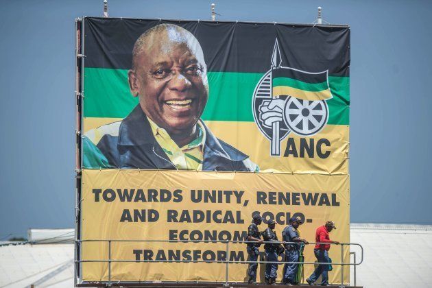 South African police officers stand by a giant portrait of ANC president Cyril Ramaphosa during the African National Congress' 106th anniversary celebrations at Absa Stadium in East London on January 13, 2018.