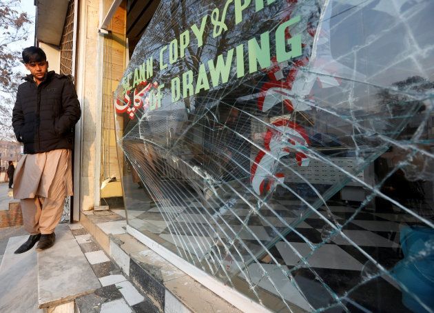 An Afghan shopkeeper looks at the broken glass window of his shop near the site of a bomb attack in Kabul, Afghanistan, January 28, 2018.