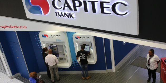 Customers queue to draw money from an ATM outside a branch of South Africa's Capitec Bank in Johannesburg.