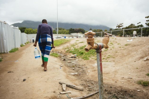 A resident carries a plastic container of water after filling from the communal tap in the Imizamo Yethu township outside Cape Town, South Africa on Nov. 13, 2017.
