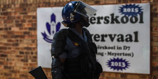 A South African riot police officer stands guard at the main entrance of Hoërskool Overvaal on January 18, 2017 in Vereeniging.