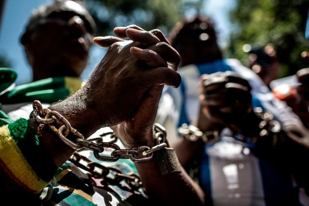 Members of the Africa Diaspora Forum (ADF), civil society organisations, churches, trade unions and other coalitions wear chains and shout slogans during a demonstration against the slave trade and human trafficking in Libya on December 12, 2017 at the Union Buildings in Pretoria.