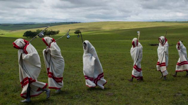 QUNU, EASTERN CAPE, SOUTH AFRICA, 14 DECEMBER 2013: Xhosa Initiates pass by close to the funeral of Nelson Mandela, Qunu, South Africa, 14 December 2014. These initiates have recently been circumsized traditionally and without anesthetic. They will spend up to two months dressed this way and learning the tradtions of Xhosa culture. Nelson Mandela, an icon of democracy, also went through this tradtional ritual. Mandela was buried at his family home in Qunu after passing away on the 5th December 2013. (Photo by Brent Stirton/Reportage by Getty Images.)