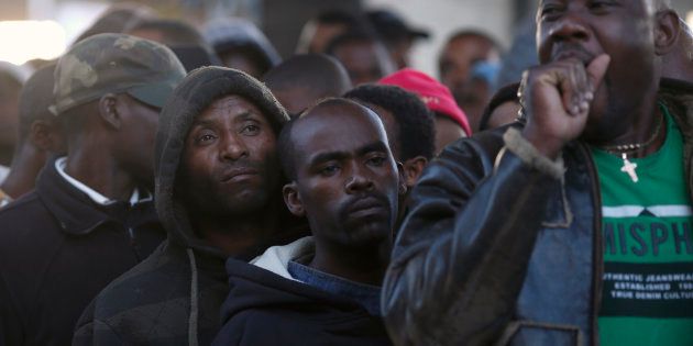 Asylum seekers queue to get their documents renewed outside a Department of Home Affairs reception centre in Cape Town on May 29, 2013.