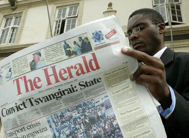 A Zimbabwean man reads a copy of the state controlled Herald newspaper outside the High Court in Harare February 25, 2004. Movement for Democatic Change (MDC) president Morgan Tsvangirai's defence team at the time was to submit their final summation on treason charges for allegedly plotting to assassinate then-president Robert Mugabe.