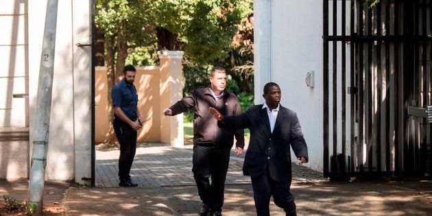 Private Security agents gesture as they stand guard outside the compound of the controversial business family Gupta in Johannesburg, on February 14, 2018.