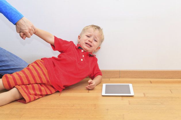 Parent pulling child from touch pad. Computer Addiction