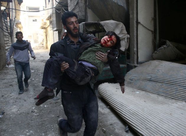 A man carries an injured boy in the rebel held besieged town of Hamouriyeh, eastern Ghouta, near Damascus, Syria, February 21, 2018.
