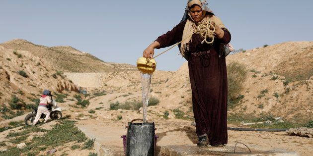 Saliha Mohamedi, 36, fills a bowl from her water storage outside her troglodyte house.