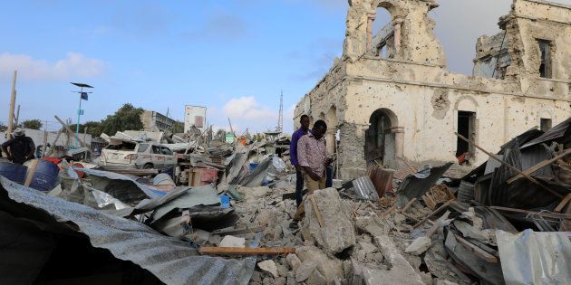 Civilians look at the scene after a suicide car explosion in front of Doorbin hotel in Mogadishu, Somalia February 24, 2018.