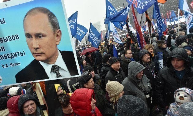People hold a placard with the picture of Russian President Vladimir Putin and flags during the 'Russia is in my heart!' rally in support of Russian athletes on February 3, 2018 in central Moscow.